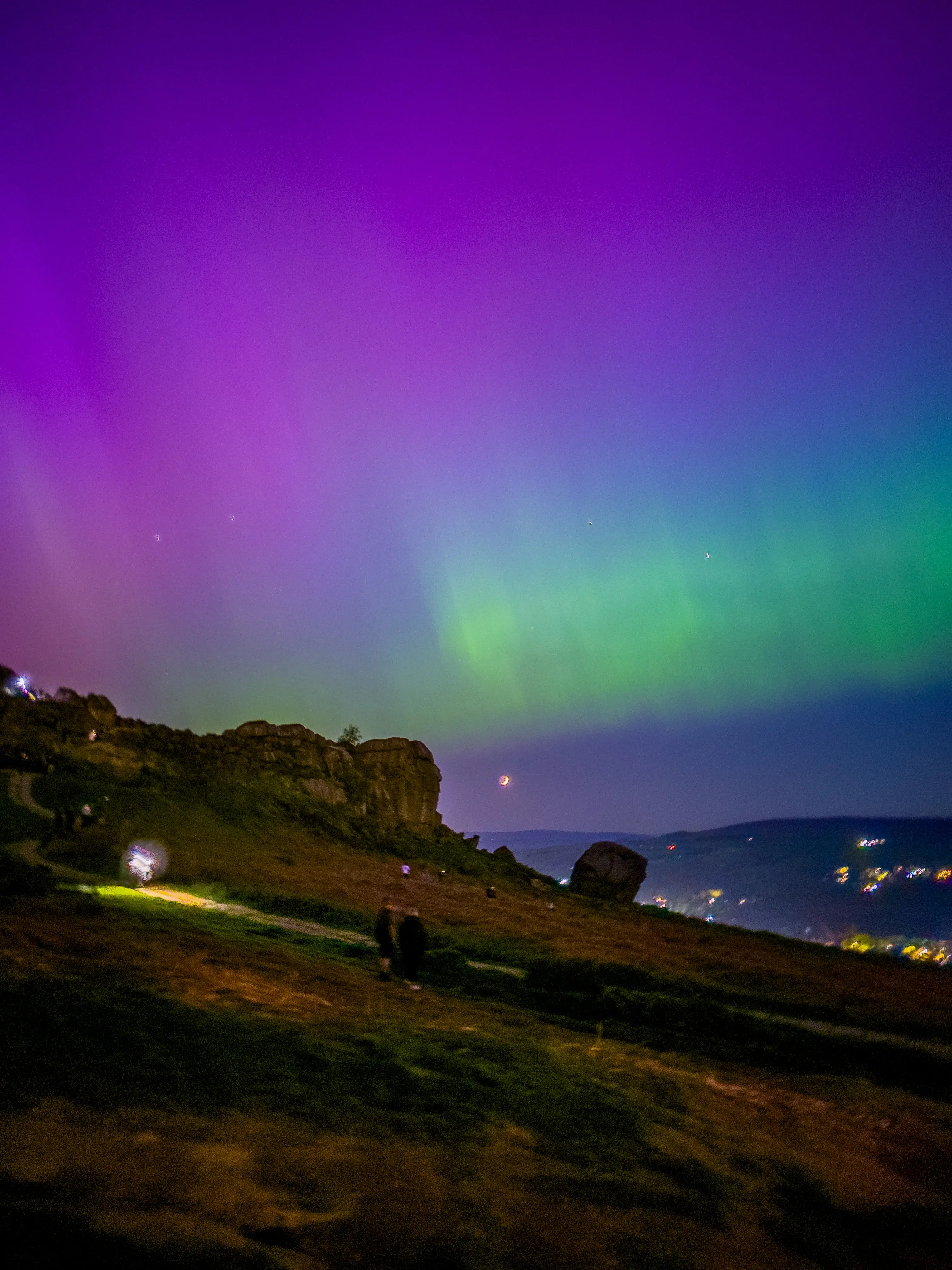Aurora Borealis glowing green and magenta over the dark contours of Ilkley Moor